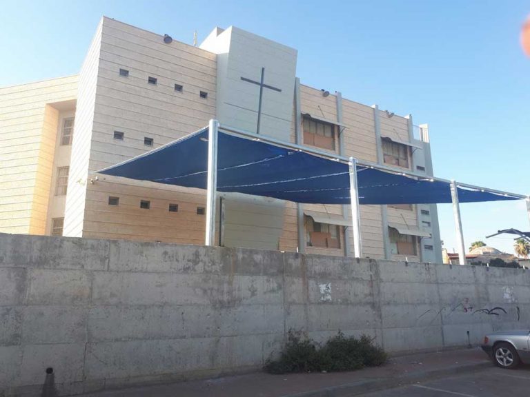 רשת 320 גר צבע כחול מותקנת בין מבנה הביה"ס לעמודים